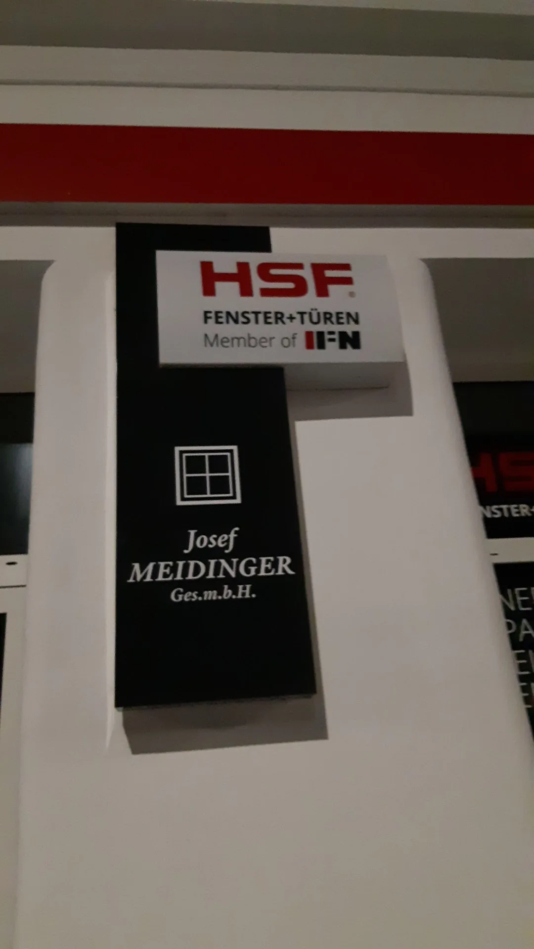 Nasenschild an der Fassade: Fensterkreuz und Schriftzug Josef MEIDINGER Ges.m.b.H., darüber ein Schild HSF Fenster+Türen
