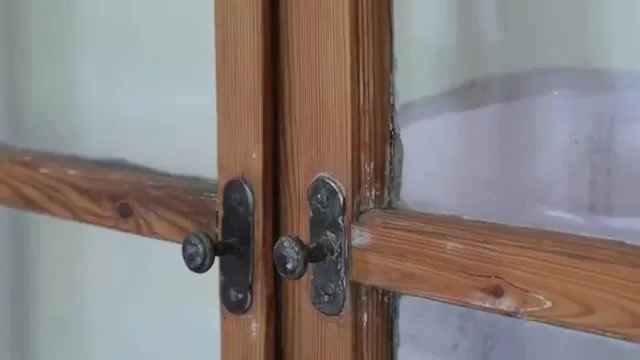 Alter Holzkastenfensterflügel mit dunklen Beschlägen und Knopfgriffen